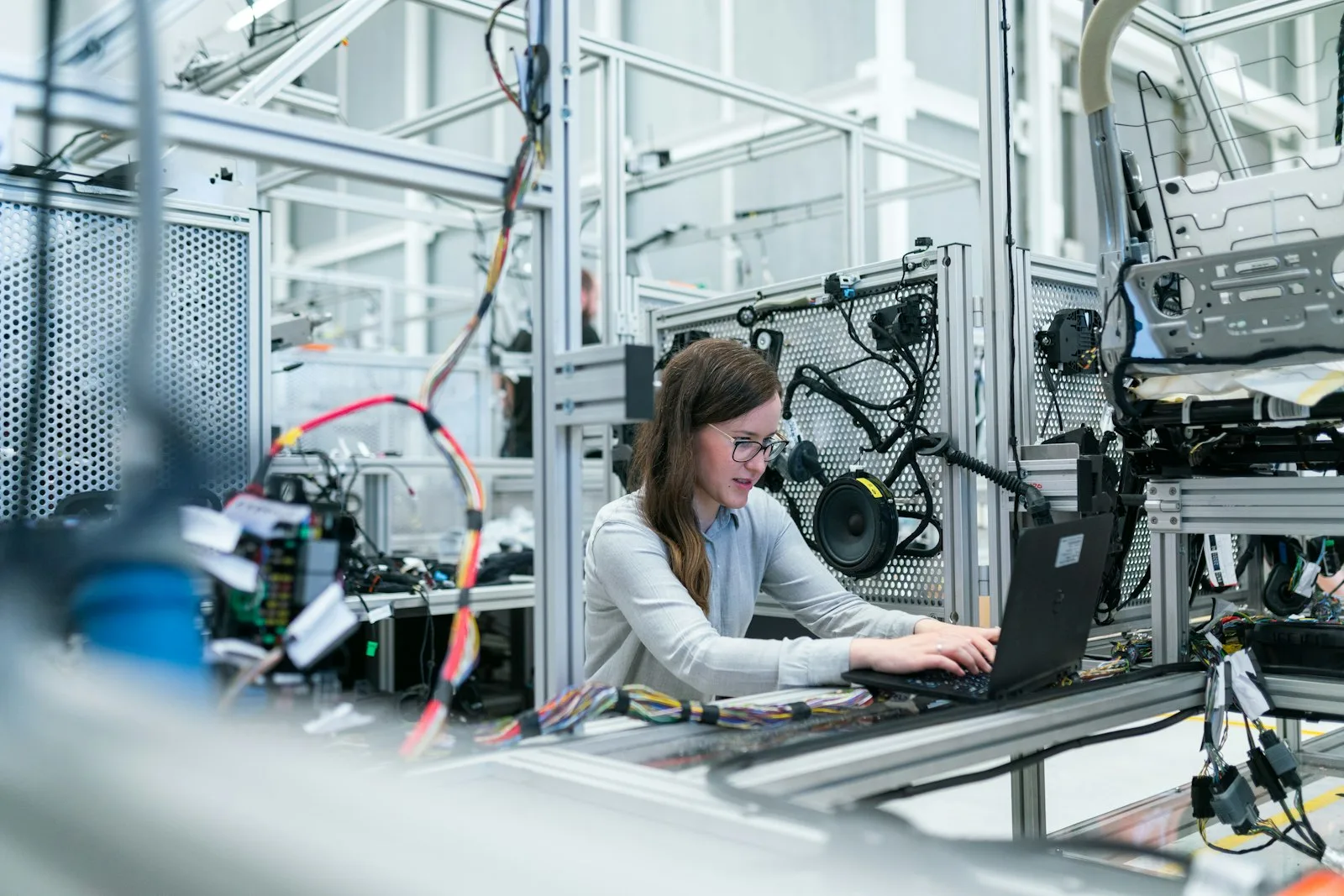 An engineer working at a laptop beside factory automation equipment